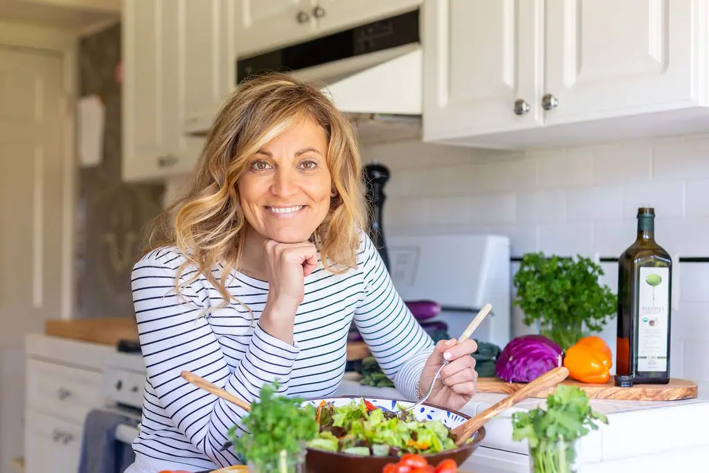 A woman sitting in front of a bowl of salad.