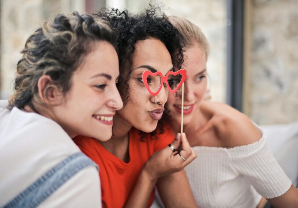 Three women are posing for a picture with heart glasses.